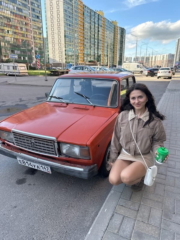 Posing beside a vintage orange car on a Murino street
