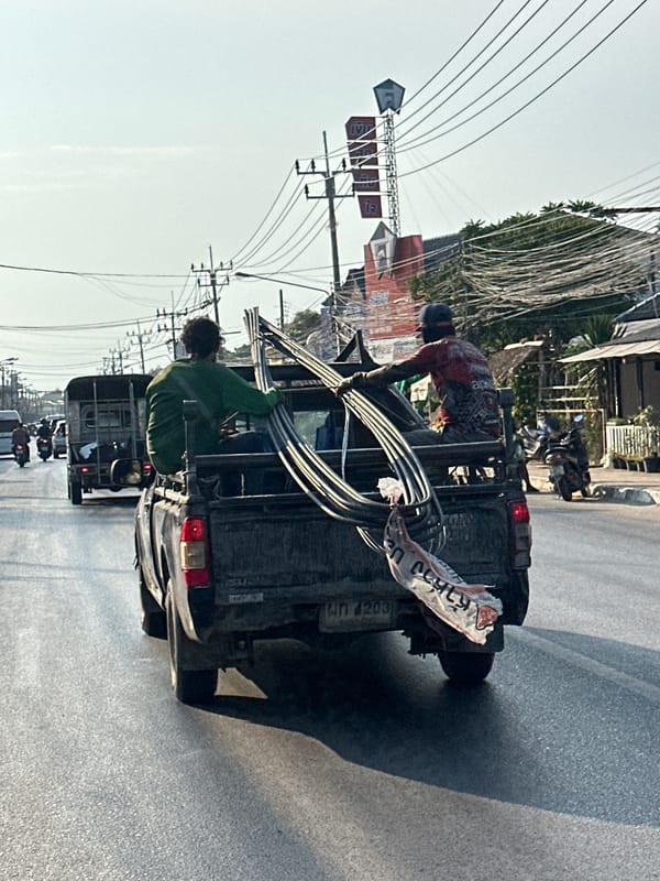 Two men handle materials from pickup truck in Thailand