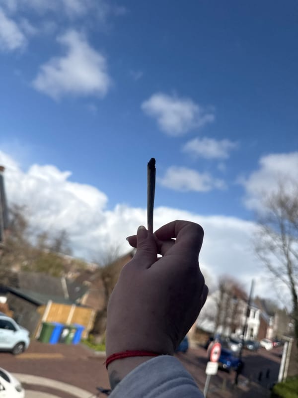 Person smoking in residential Sliedrecht neighborhood under blue sky