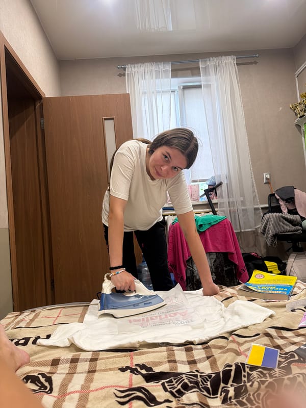 Ironing a t-shirt in a Dnipro bedroom, trophies on the wall