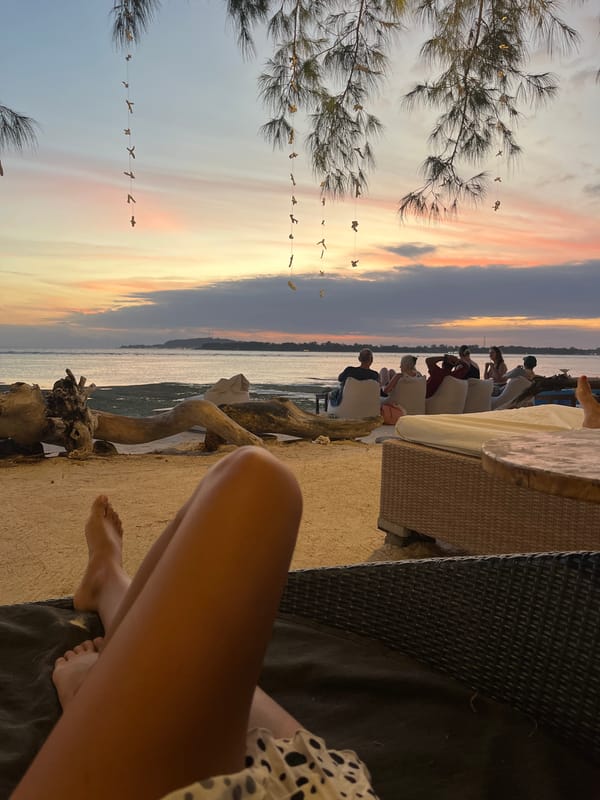 Six people watch sunset from beach chairs in Indonesia