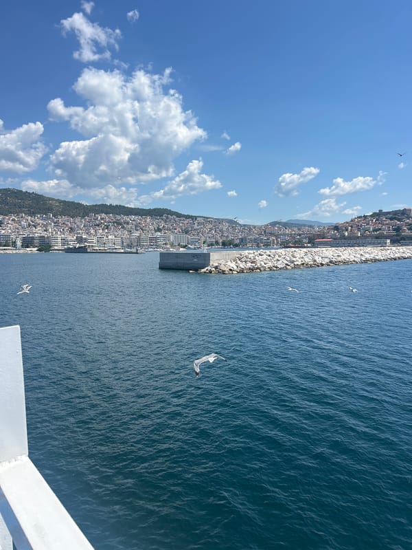 Ferry crossing toward a hillside coastal city on a sunny day