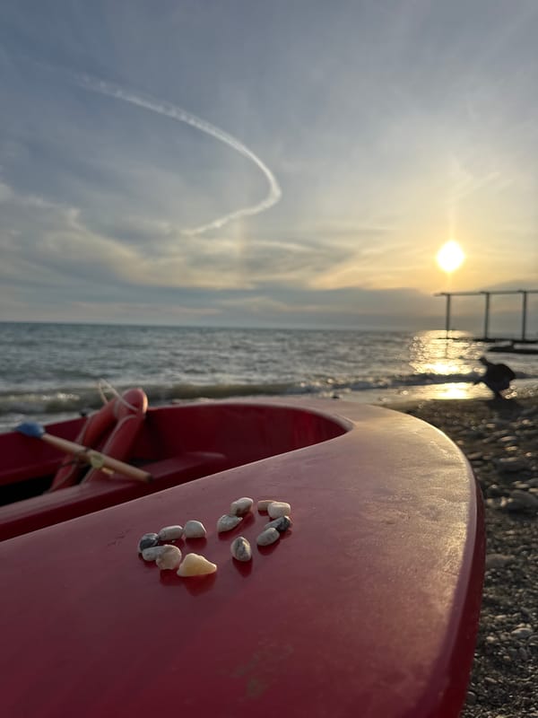 Golden hour on Sochi's pebble beach, red boat and all