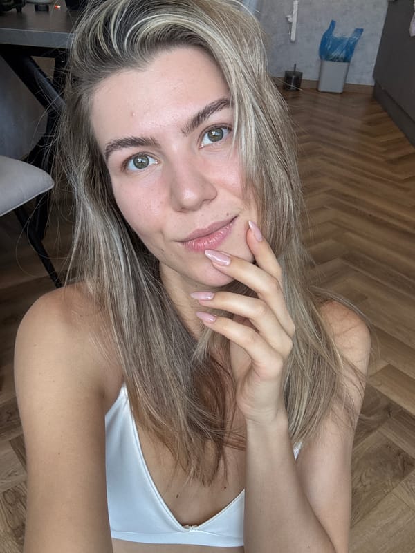 Woman takes selfies in white top, blonde hair visible