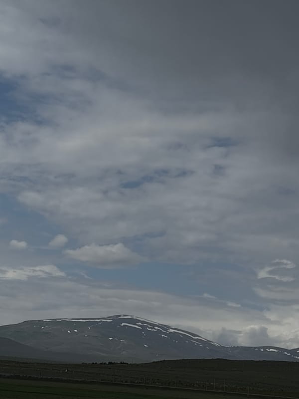 Cloudy skies and snow-capped mountains observed near Tlik, Armenia