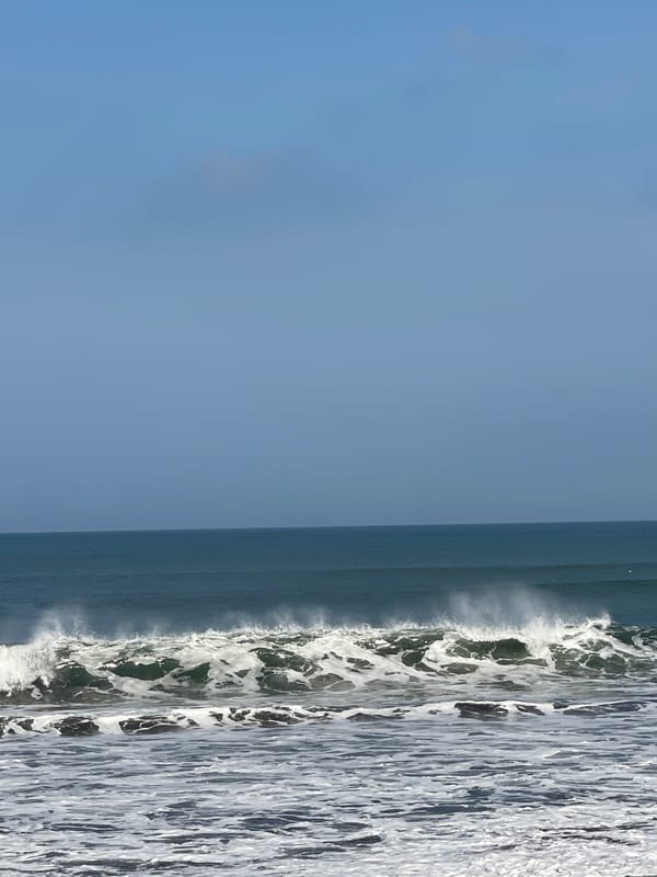 Dark sand beach day in Kediri with waves and a burn mark