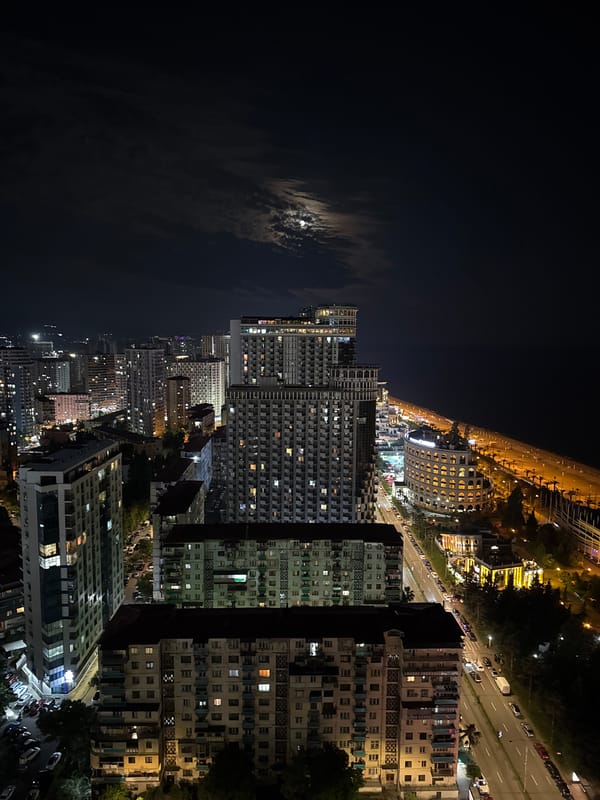 Batumi's nighttime skyline from above, coastal city lit up