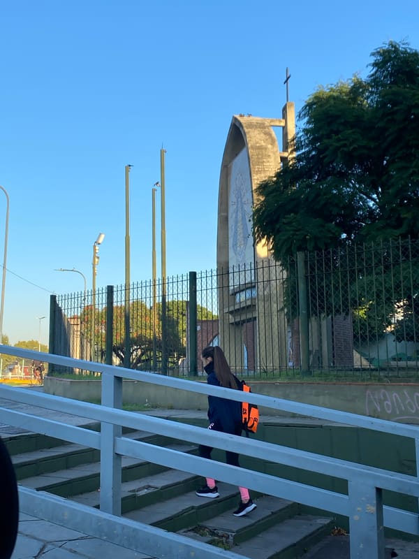 Pedestrian walks past fenced religious building in Buenos Aires
