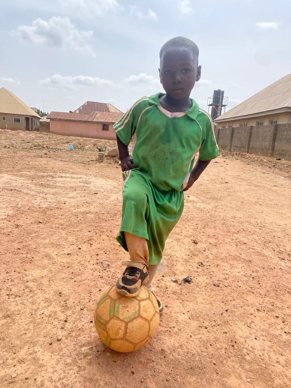 Young boy stands in dirt area in Rido, Nigeria