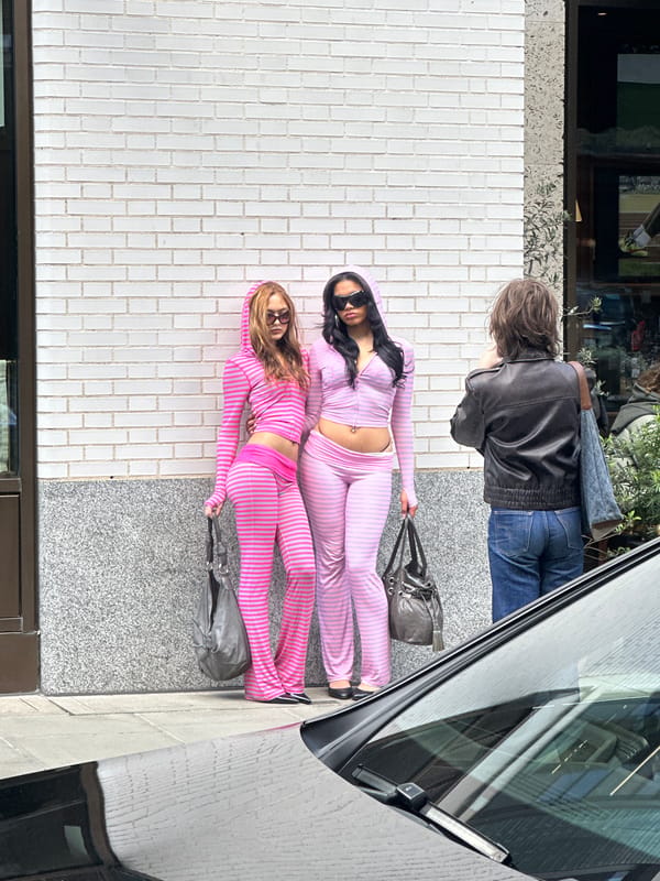 Two women in matching tracksuits lie on London pavement