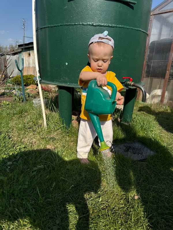 Baby with watering can observed near green tank in Noviy