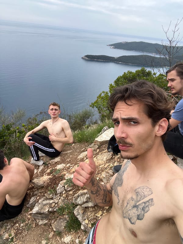 Four tourists pose on rocky cliff near Sveti Stefan