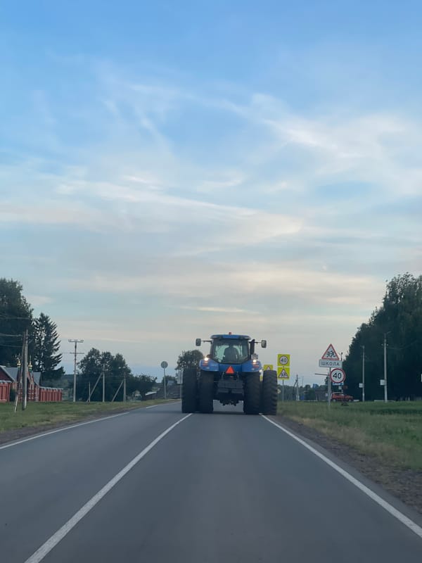 Tractor passes Orthodox church on a quiet Russian village road