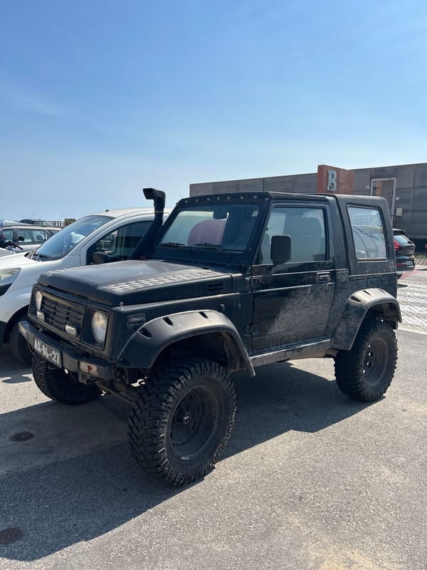 Lifted Suzuki Samurai and yellow Mercedes van parked on a sunny day