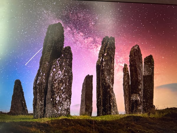 Ancient standing stones under a colorful night sky