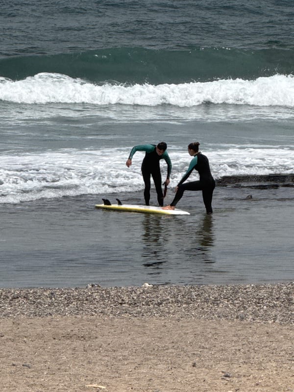 Arona beach day: surfers, lifeguard tower, and promenade life