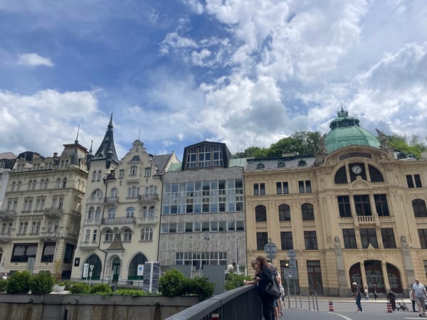 Tourists document Karlovy Vary's historic architecture during overcast morning