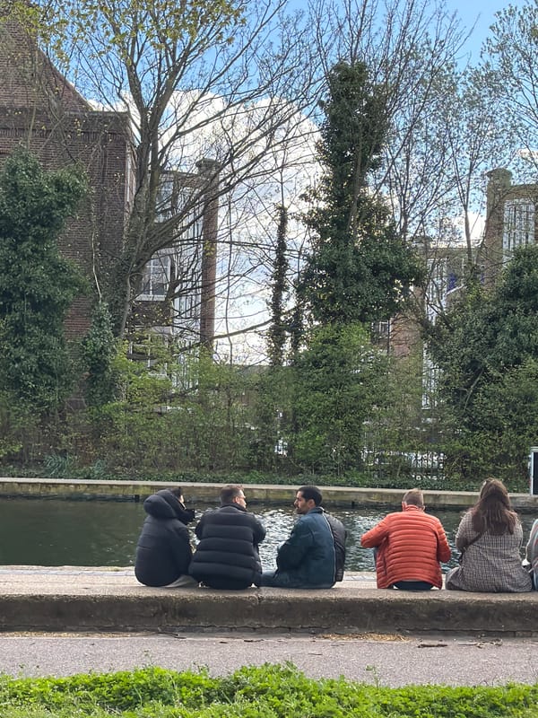 Four people sit by London canal in cool weather