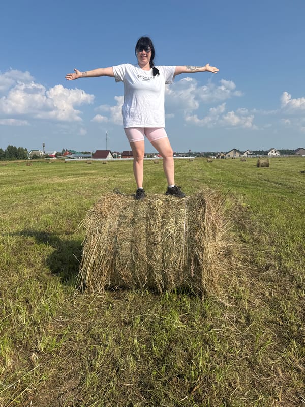 Balancing on a hay bale in a Russian summer field