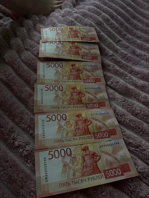Person photographed with Russian currency and jewelry on blanket