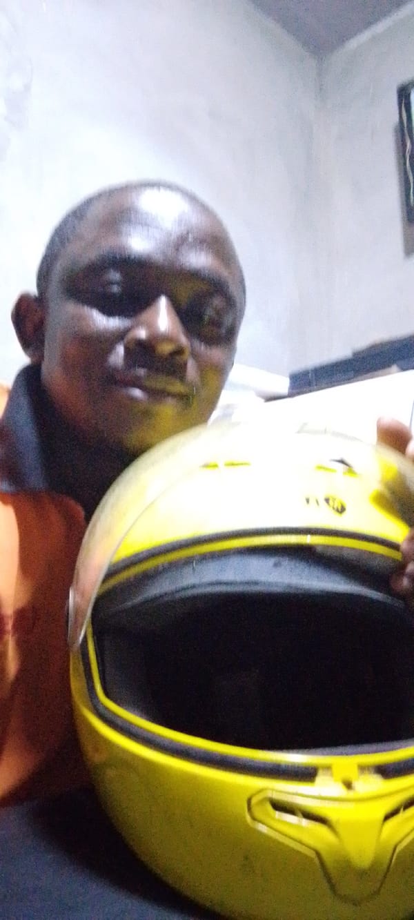 Man holds yellow helmet indoors in Lokoja, Nigeria