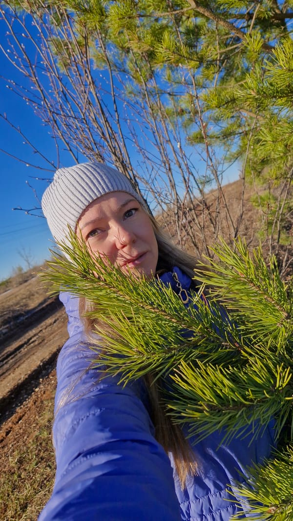 Young woman takes selfie among evergreens in Otchor, Russia