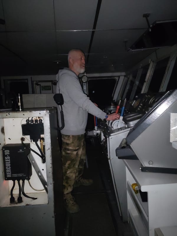 Man operates vessel bridge controls at night in Golyashi