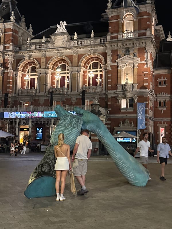 Amsterdam at night: historic theater, teal hand sculpture, cyclists