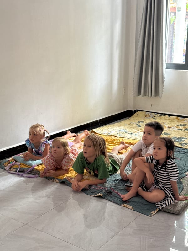 Children watch morning cartoons on living room floor in Vietnam