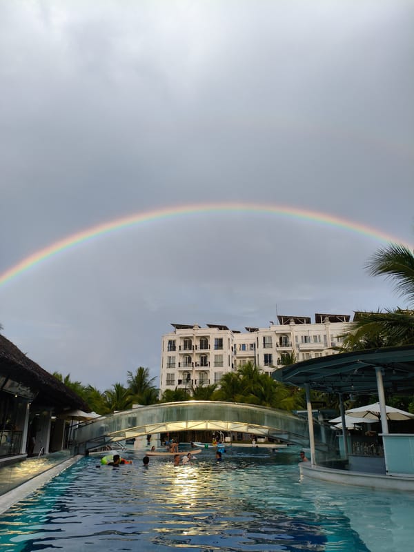 Rainbow over a Nha Trang resort pool on a cloudy morning
