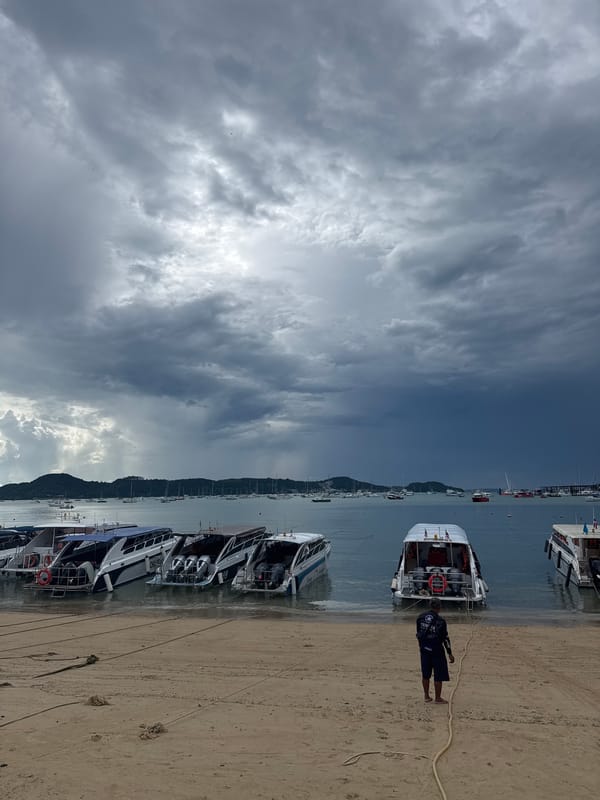 Chalong Bay under stormy skies, speedboats lined along shore