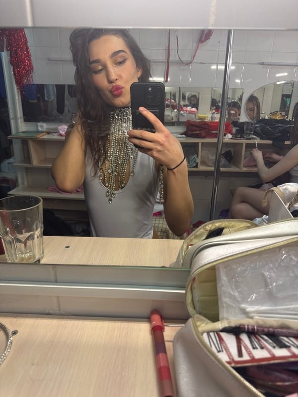 Person takes mirror selfie in white jeweled top