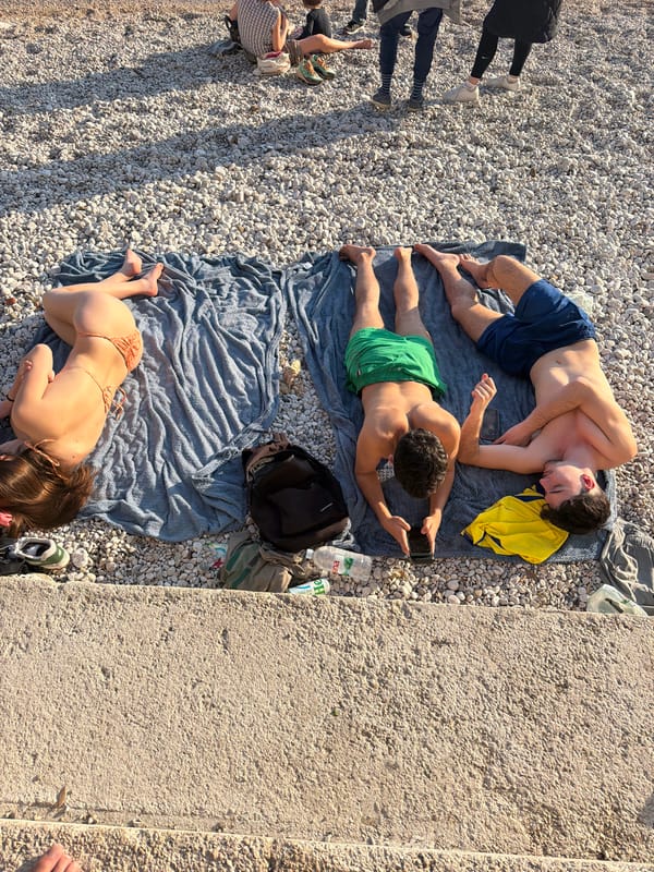 Beachgoers relax on pebble beach in Rijeka, Croatia