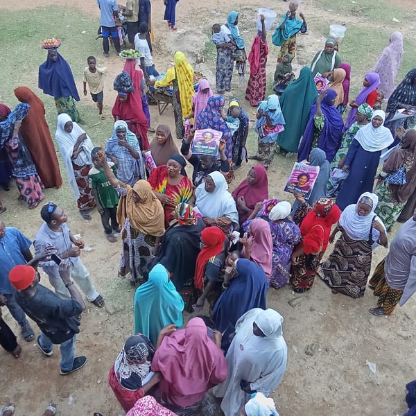 Women gather in dusty open area, location unknown