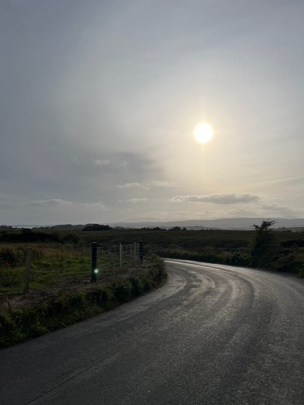 Wet roads and hay bales across a quiet Irish rural landscape