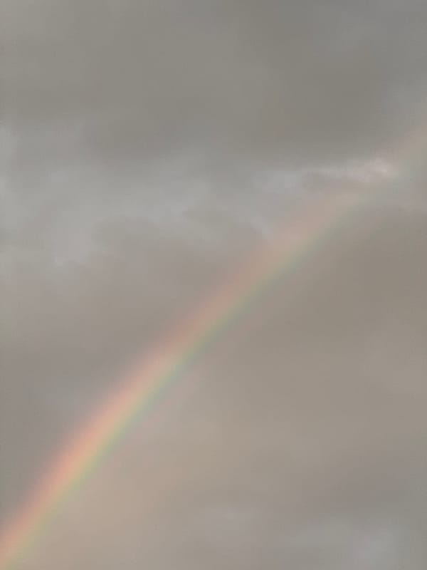 Faint rainbow over residential rooftops in Mikhaylovsk at dusk