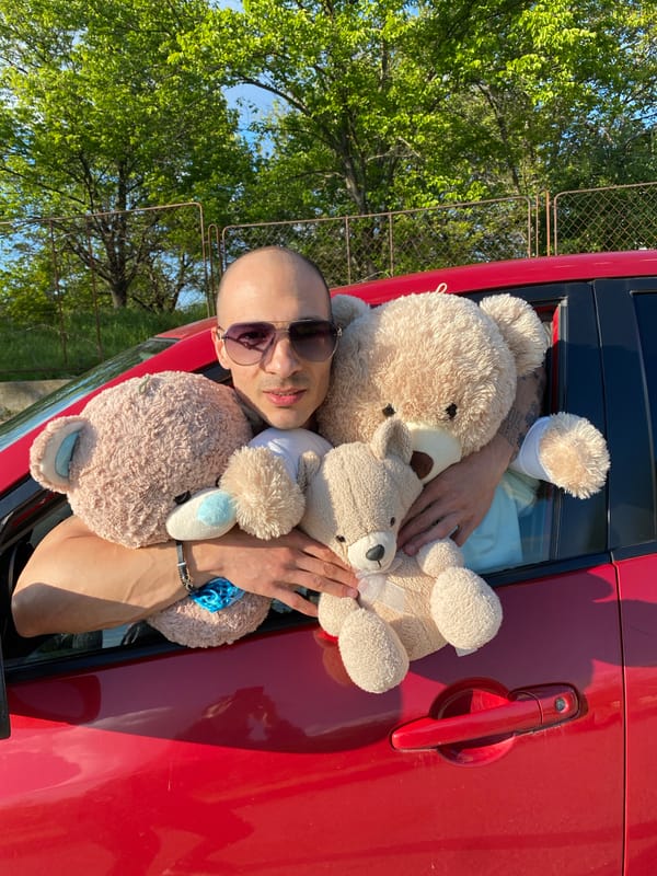 Person poses with teddy bears and red car in Bulgaria