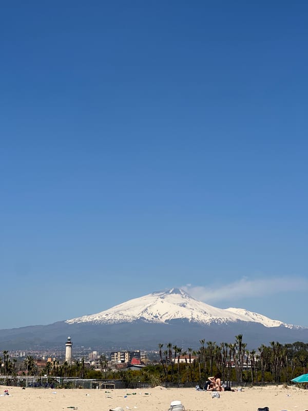 Beachgoers enjoy sunny day in Catania with Mount Etna backdrop