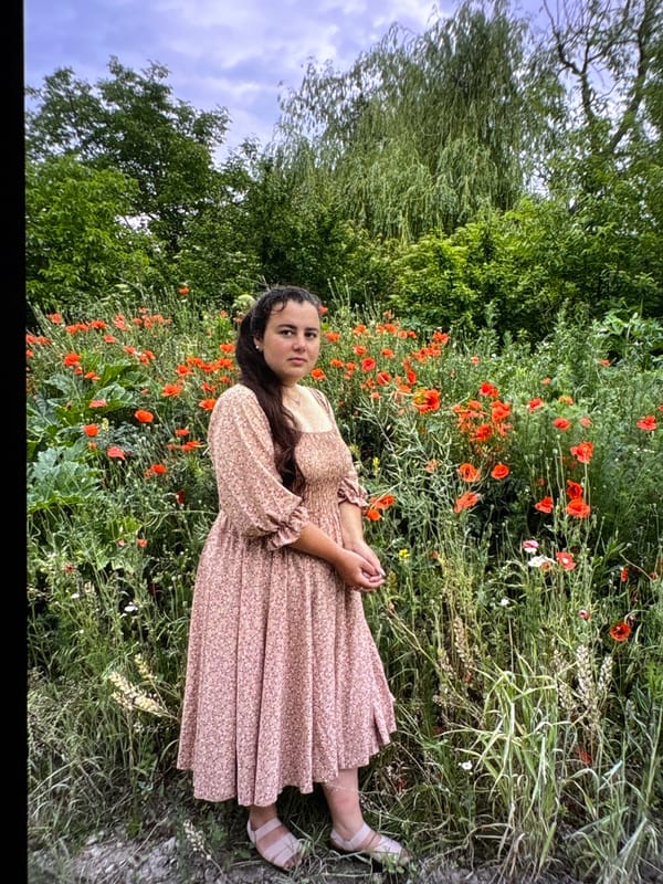 Posing among red poppies in a floral dress