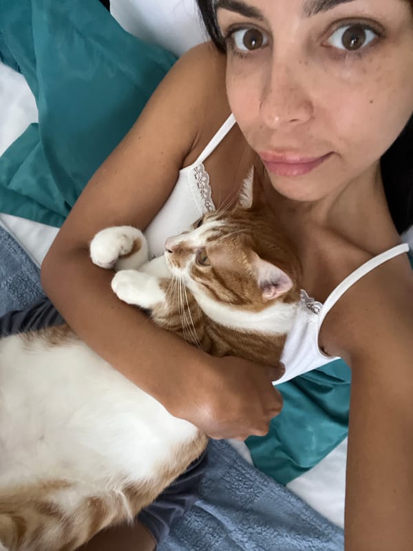 Woman cuddles with orange tabby cat in Indonesia bedroom