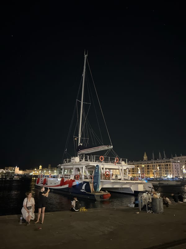 White catamaran docked at a Marseille marina after dark