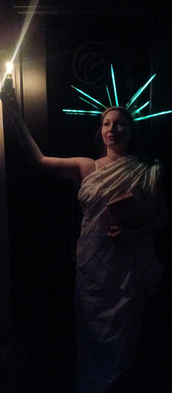 Person in glowing Statue of Liberty costume spotted under neon lights