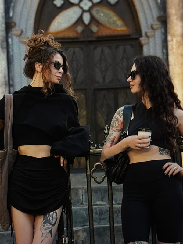 Two women in black pose near railings in Đà Nẵng