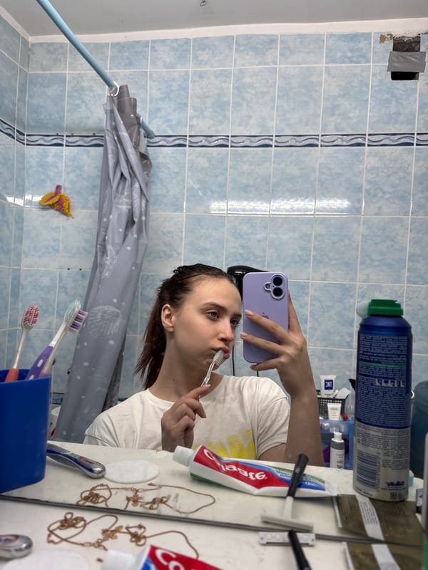 Person takes mirror selfies with purple phone in Russian home