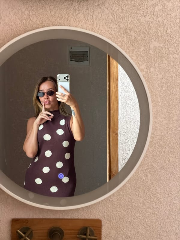 Mirror selfie in a warmly lit Mengwi bathroom, polka-dot dress