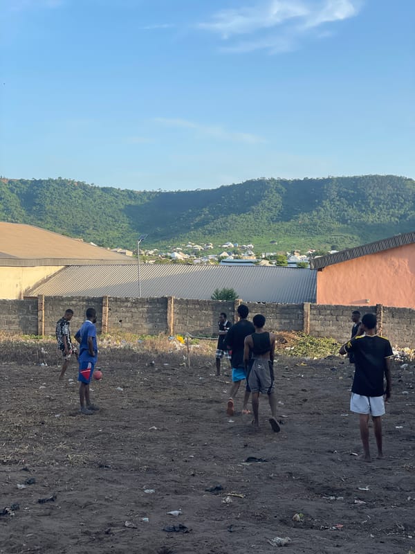 Pickup soccer on a rough dirt lot in a semi-urban neighborhood