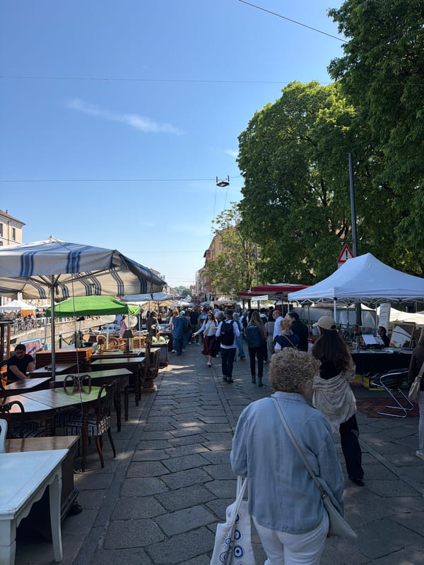 Market crowd walks between vendor stalls in Milan
