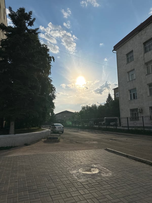 Quiet Kokshetau street at golden hour, sedan parked roadside