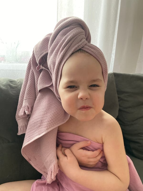 Child in pink towel turban rests on sofa in Izhevsk