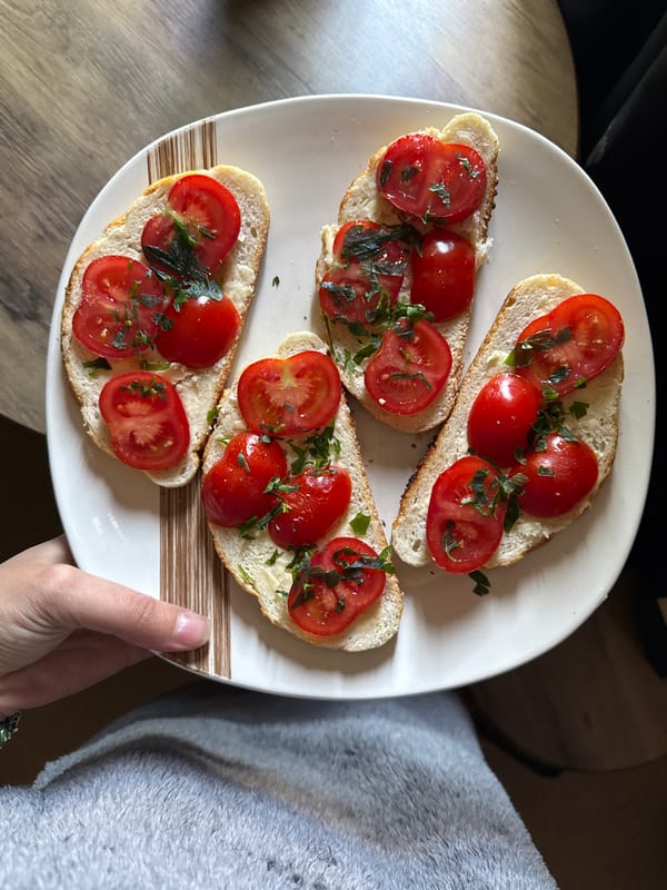 Person holds tomato-herb topped baguette slices in Great Yarmouth